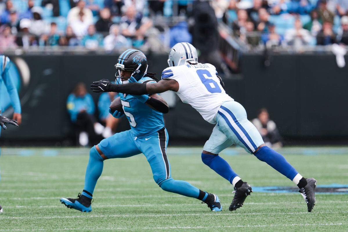 Oct 12, 2025; Charlotte, North Carolina, USA; Carolina Panthers running back Rico Dowdle (5) is tackled by Dallas Cowboys safety Donovan Wilson (6) during the first half at Bank of America Stadium. Mandatory Credit: Scott Kinser-Imagn Images