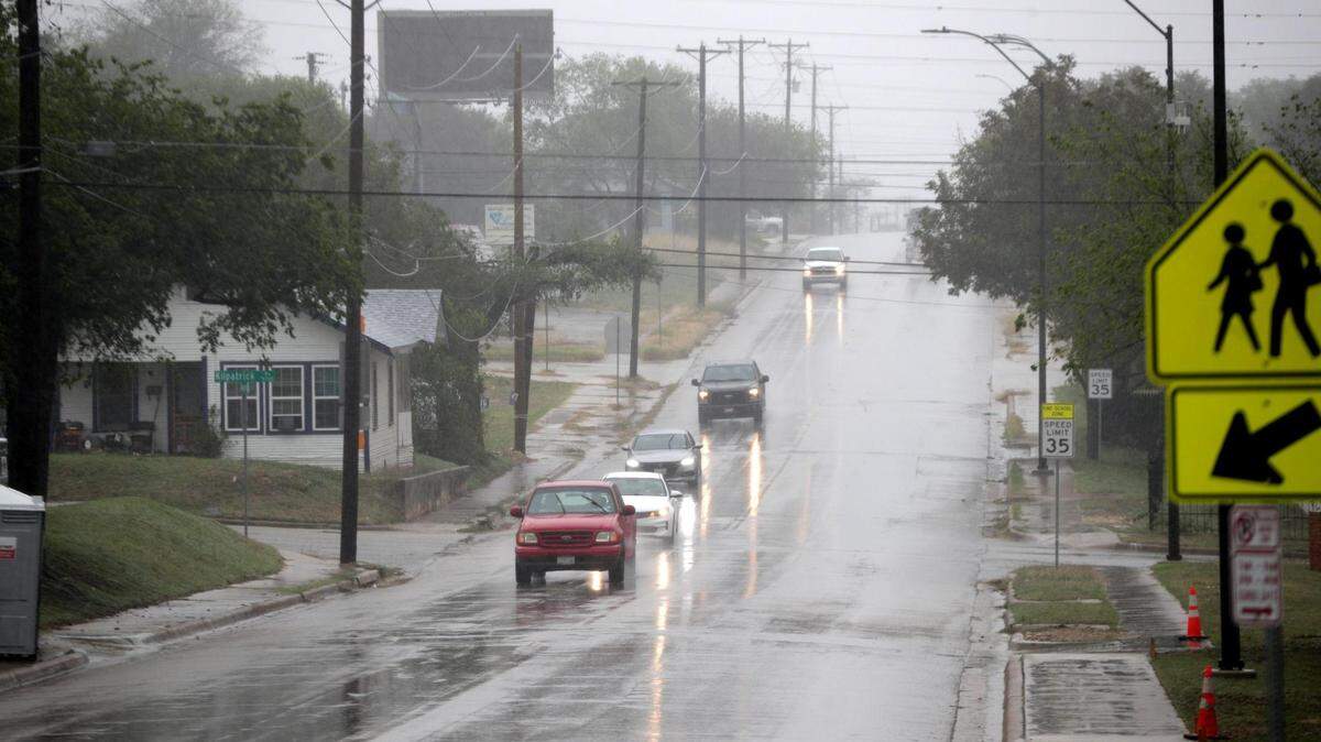 Cars pass through rainy neighborhoods in Fort Worth as storms moved into the area on Friday.