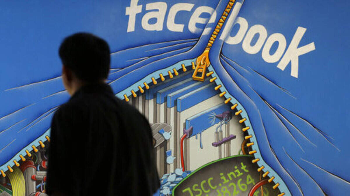 FILE - In this June 11, 2014, file photo, a man walks past a mural in an office on the Facebook campus in Menlo Park, Calif.