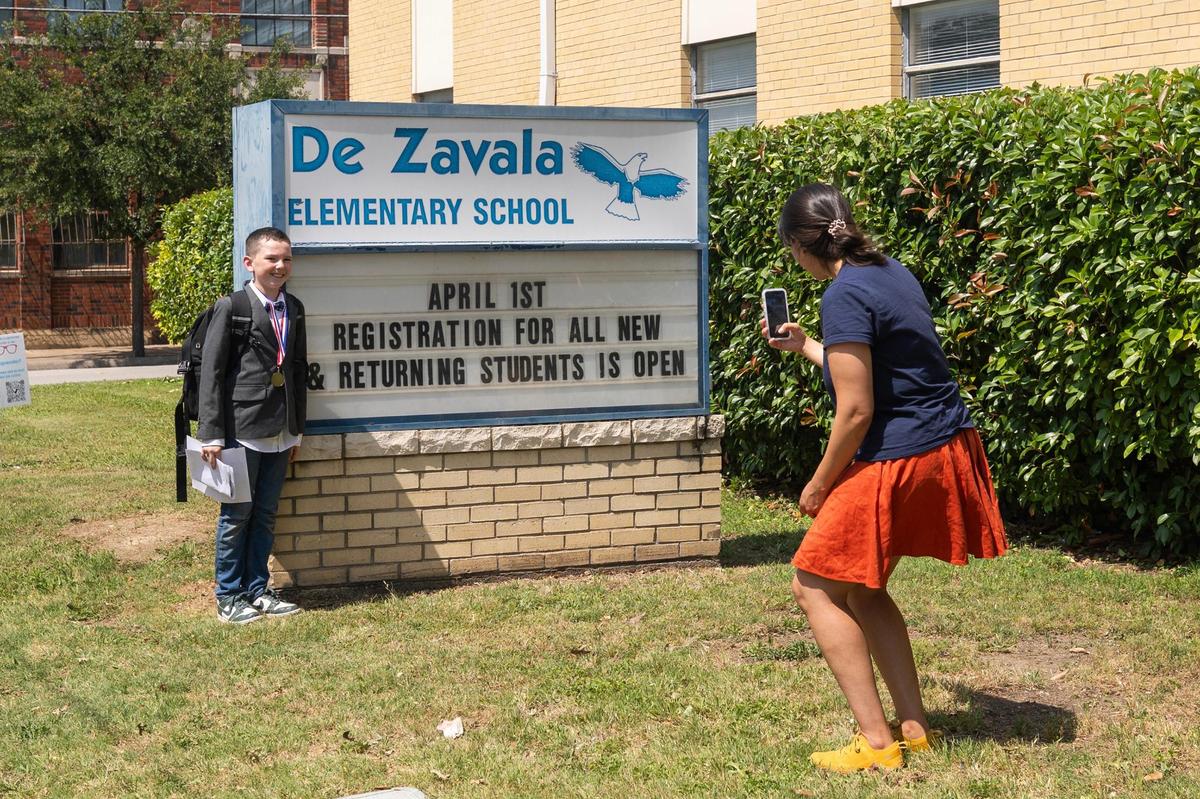 Fourth-grader Oliver Trimble, 10, has his photo taken by his mother, Natalie Lozano Trimble, at the school sign after the students’ final day of the school year at De Zavala Elementary School in Fort Worth on May 22.