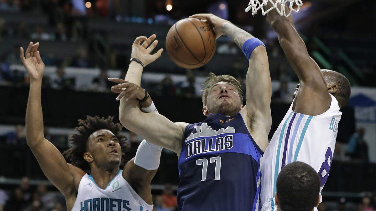 Dallas Mavericks’ Luka Doncic (77) is fouled as he drives between Charlotte Hornets’ Devonte’ Graham (4) and Bismack Biyombo (8) during the second half of an NBA basketball game in Charlotte, N.C., Wednesday, Jan. 2, 2019. (AP Photo/Chuck Burton)