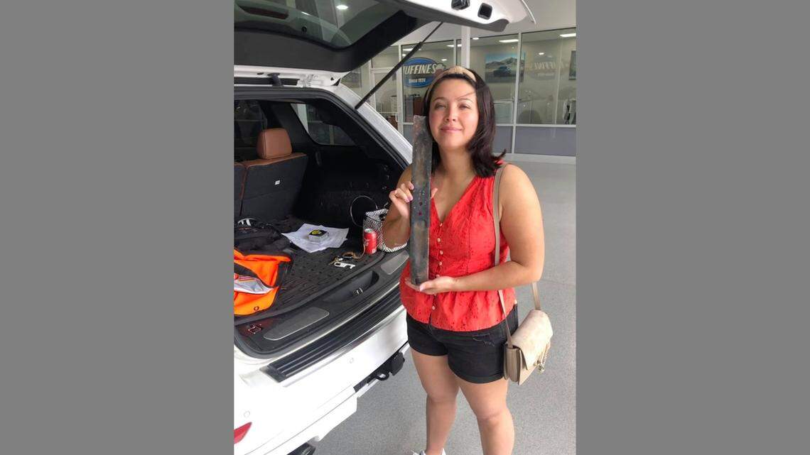 Lauren Drum of Plano, Texas, holds the lawn mower blade she says came hurtling through the windshield of her husband’s car as they drove along I-635.
