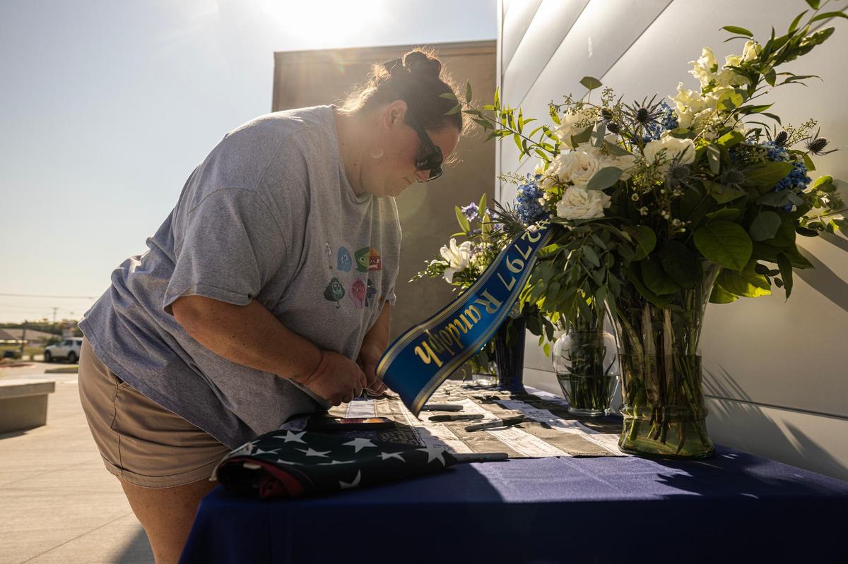 Amanda Resendez writes a message on the memorial of the late Fort Worth Police Department Sgt. Billy Randolph at Fort Worth PD South Division headquarters in Fort Worth on Tuesday, Aug. 13, 2024. Sgt. Randolph was struck by a vehicle while working a crash scene on the exit ramp of IH-35W near Sycamore School Road Monday morning.