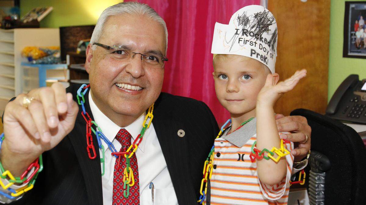 Judah, an Arlington pre-kindergarten student, helps Superintendent Marcelo Cavazos accessorize his suit. The superintendent visited Arlington schools on the first day of class.