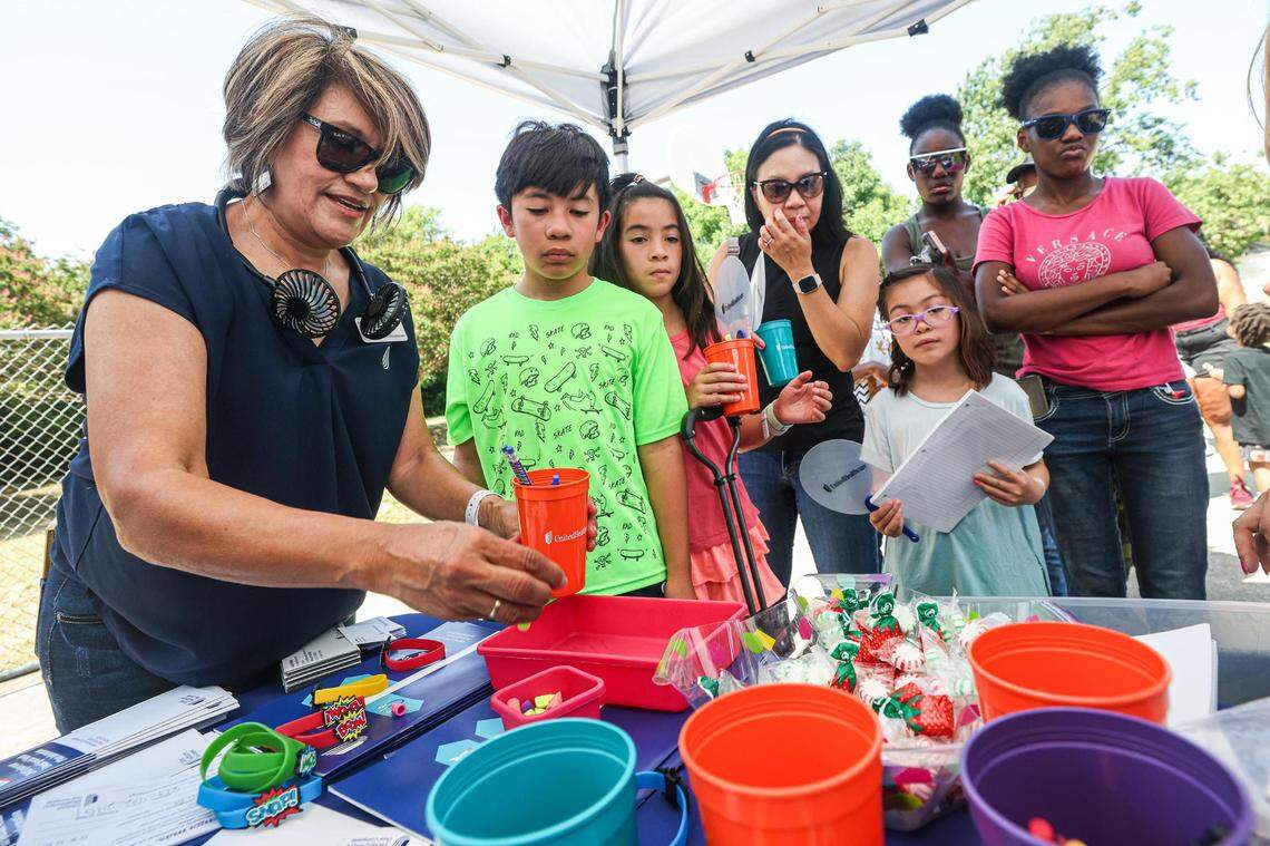 Parents and children line up to receive free school supplies from Lucy Whitley, a sales agent for United Health Care, during the annual Back to School Bash at Thomas Place Community Center in Fort Worth on July 26.