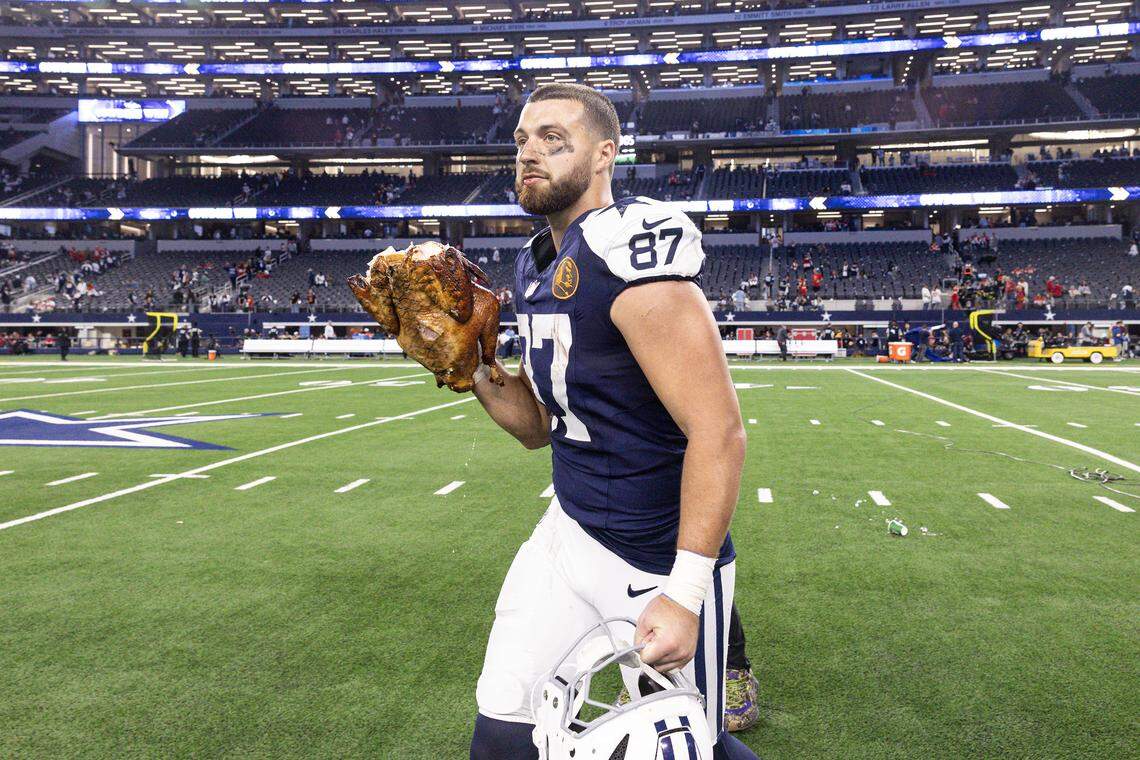 Cowboys tight end Jake Ferguson (87) runs into the locker room with the turkey on his hand after winning an NFL game between the Dallas Cowboys and the Kansas City Chiefs at AT&T Stadium in Arlington on Thursday, Nov. 27, 2025. The Cowboys won 31-28.
