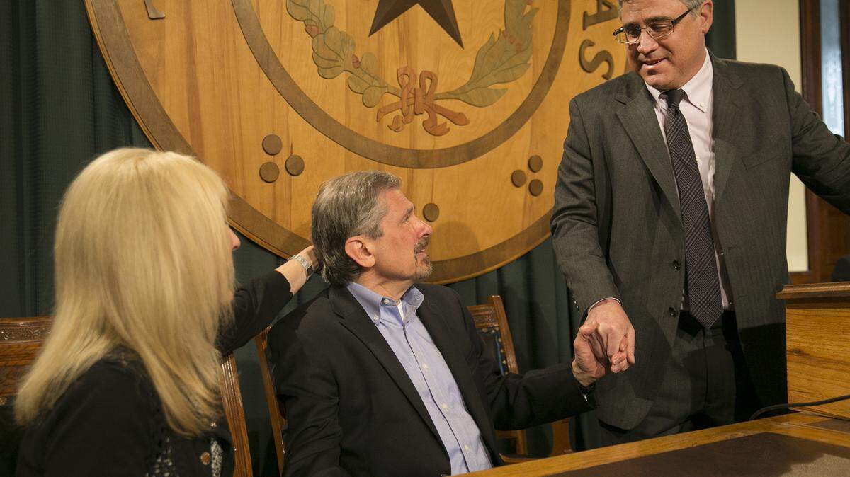 Kent Whitaker, center, reacts to the his lawyer Keith Hampton, right, reading an email from the Texas Board of Pardons and Paroles which voted unanimously to recommend clemency for death row inmate Thomas Whitaker, Kent's son who was found guilty of setting up an ambush that killed his mother and brother in 2003. At left is Kent's wife Tanya, whom he married later. Despite the crime, his father had waged a desperate campaign to spare his life before Thursday's scheduled execution.