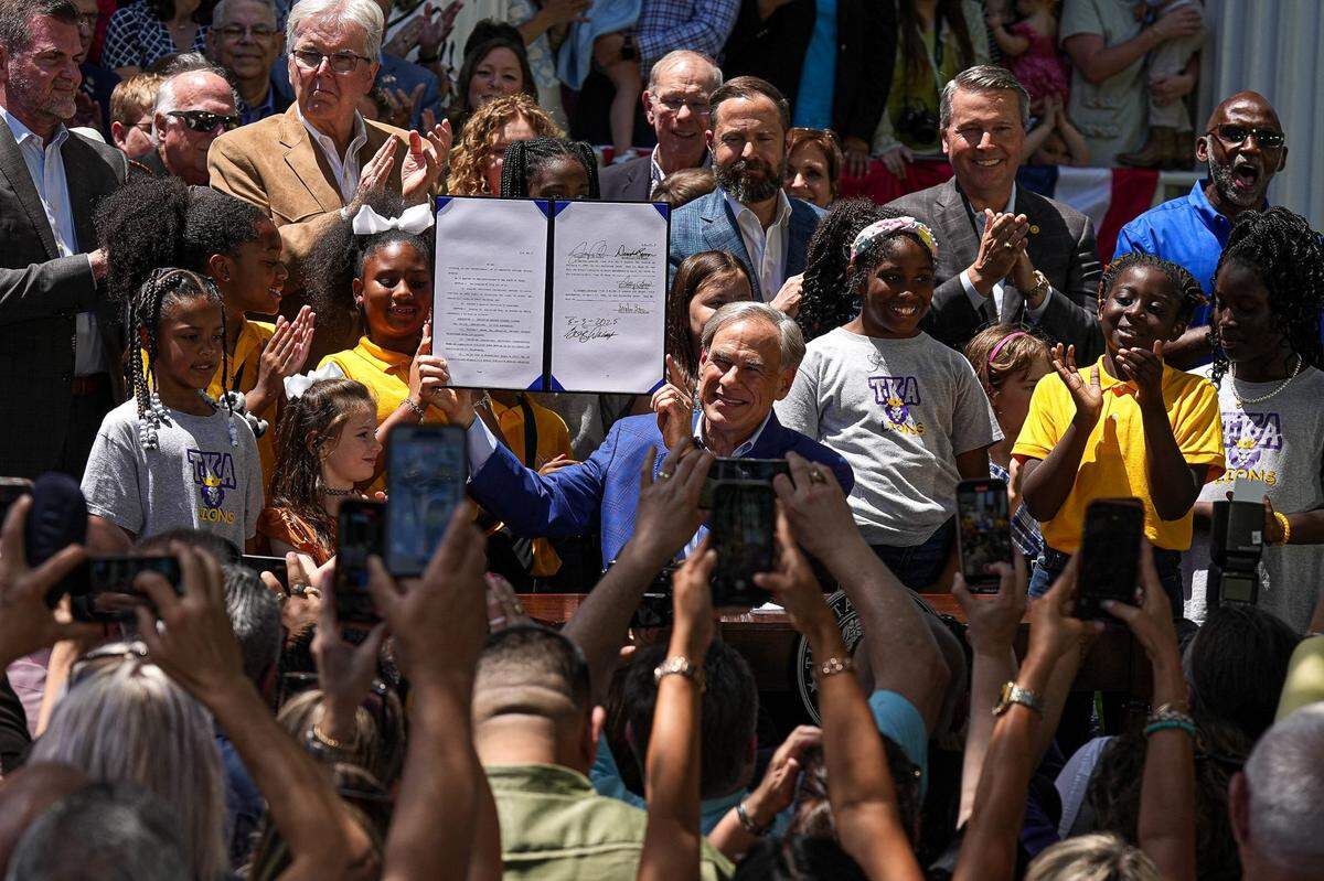 Texas Governor Greg Abbott holds up Senate Bill 2 which he signed into law at the Governor’s Mansion on Saturday, May 3, 2025 in Austin.