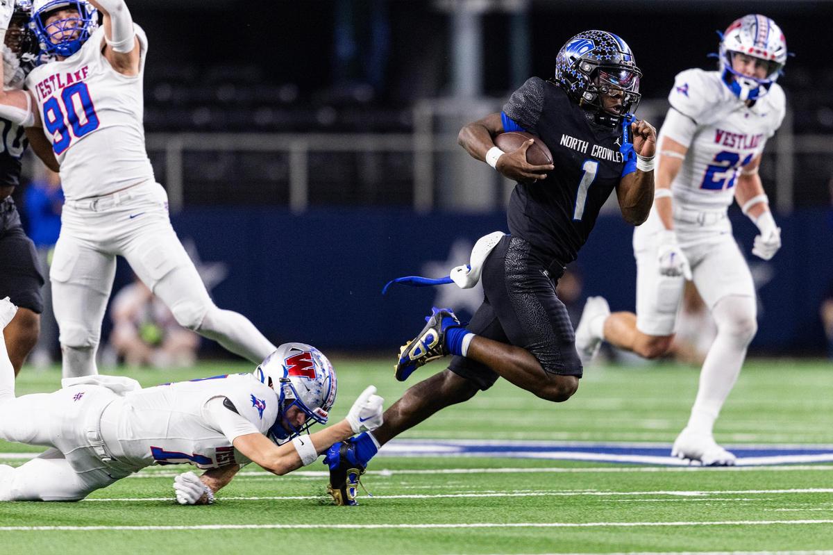 North Crowley running back Cornelius Warren III (1) gets tackled by the ankle from Westlake defensive back Evan Kolander (11) in the first quarter of the UIL 6A Division I championship game at AT&T Stadium in Arlington on Saturday, Dec. 21, 2024.