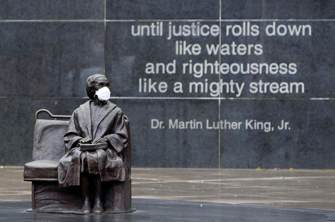 A memorial statue of Rosa Parks wears a mask at a bus stop in downtown Dallas, Friday, April 3, 2020.
