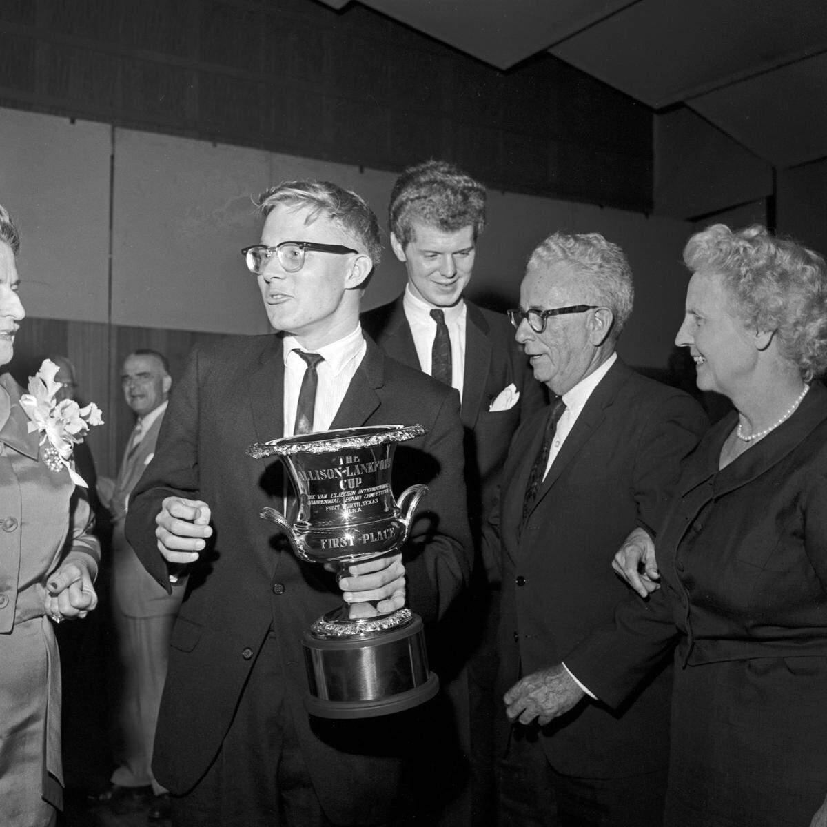 Ralph Votapek, winner of the first Van Cliburn International Piano Competition in 1962, holds the Allison-Lankford Gold Cup. The 18-inch high engraved trophy is named in honor of Irl Allison of Austin, president of the National Guild of Piano Teachers, which he founded. Dr. and Mrs. Allison contributed to the first place prize money in the name of the guild. The trophy is also named in honor of Grace Ward Lankford, co-founder of the Fort Worth Piano Teachers Forum, and founder and twice chairman of the Van Cliburn International Piano Competition. From left are Votapek, Van Cliburn, Dr. Irl Allison, and Mrs. Jessie Allison.