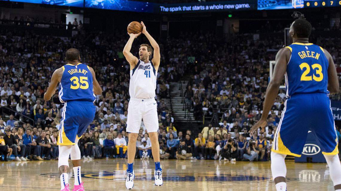 Dallas Mavericks forward Dirk Nowitzki (41) takes a three-point shot as Golden State Warriors forward Kevin Durant (35) watches in the first half of an NBA basketball game Saturday, March 23, 2019 in Oakland, Calif. (AP Photo/John Hefti)