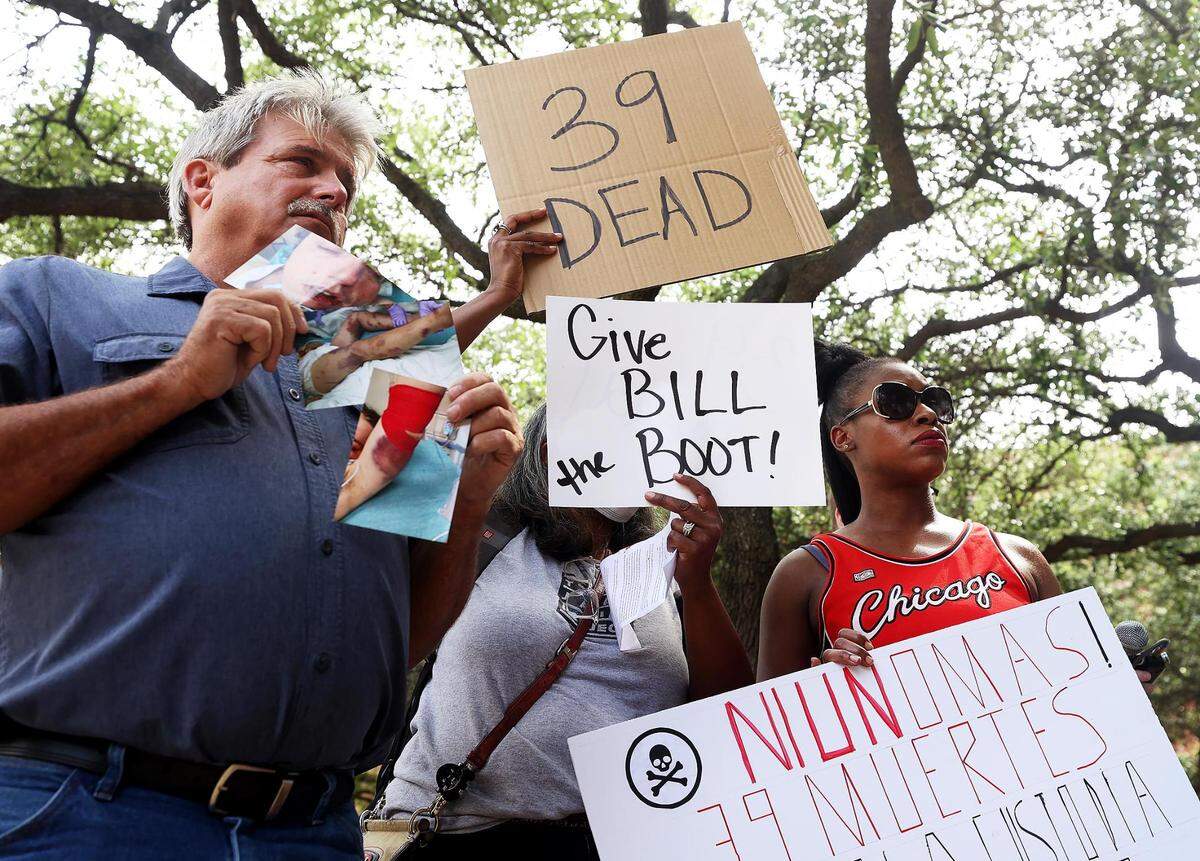 Danny Masten, left, and Shanelle Jenkins, right, hold signs during a rally outside the Tarrant County Court of Commissioners meeting on Tuesday, May 10, 2022, to demand changes at the Tarrant County jail.