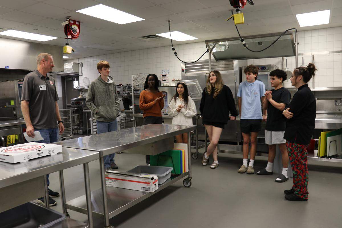 (left) Kevin McNamara, co-owner of Wise Guys Pizzeria in Grapevine, and Culinary instructor, aylie Kotecki (far right) chat with studenst about the project in the Grapevine High School’s CTE kitchen.