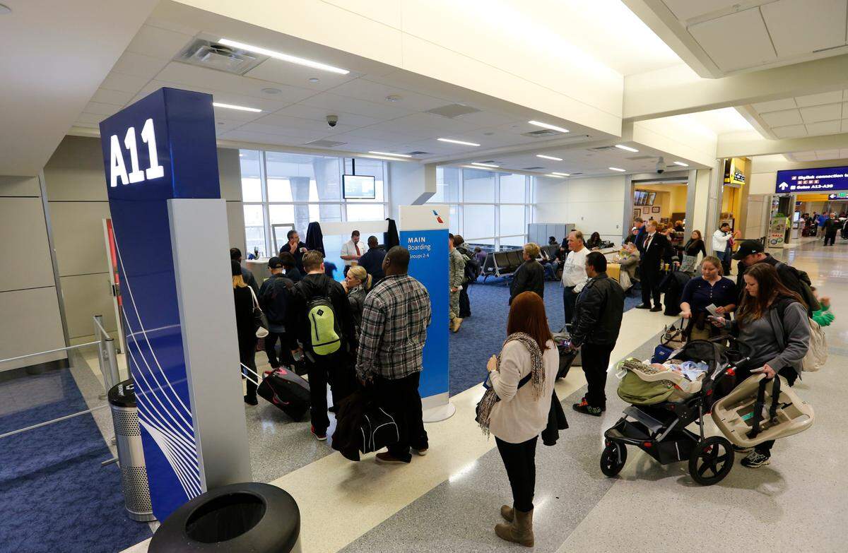 Passengers line up to board a plane at Terminal A in the Dallas/Fort Worth Airport, Wednesday, January 8, 2014.