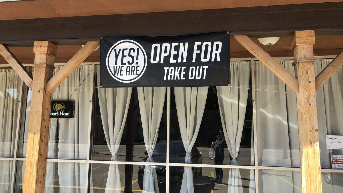 A sign hangs outside Arlington’s The Tin Cup, a panini shop, advertising they are open amid the coronavirus pandemic. The sign was created by Arlington-based Main Street Signs and Graphics and handed out for free to locally owned eateries to support their business.