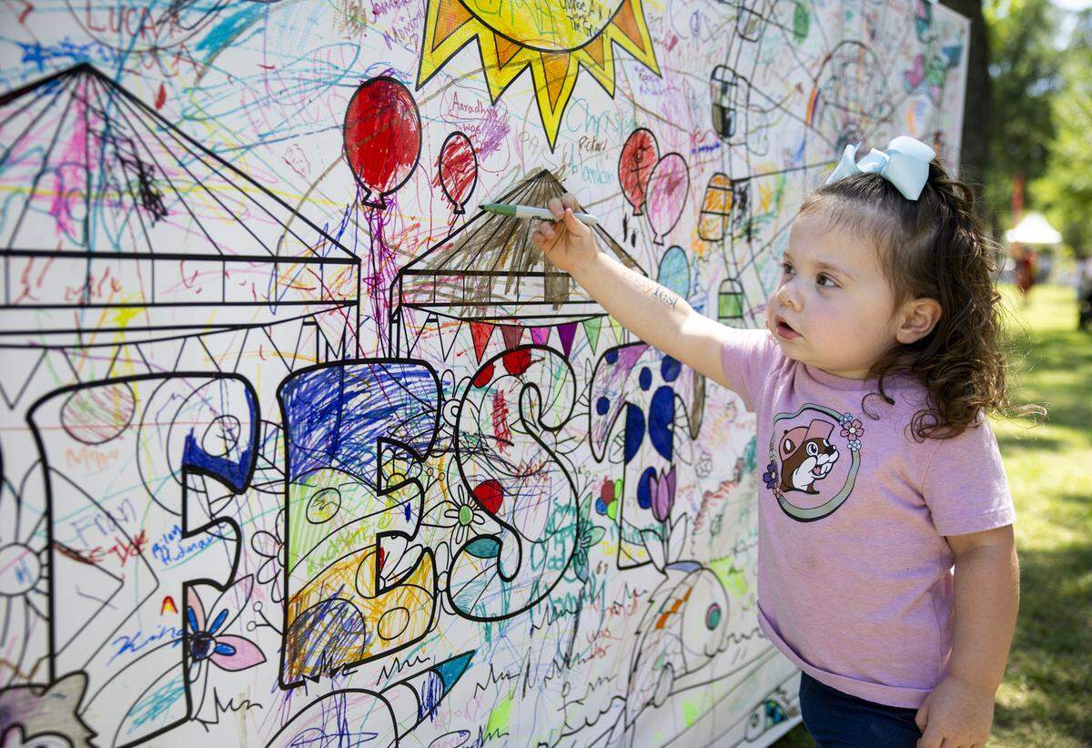 Nora Gibson, 2, colors on a community mural near the children's area of Mayfest on Saturday, May 2, 2026, in Fort Worth, Texas. The children's area featured a variety of activities for all ages.
