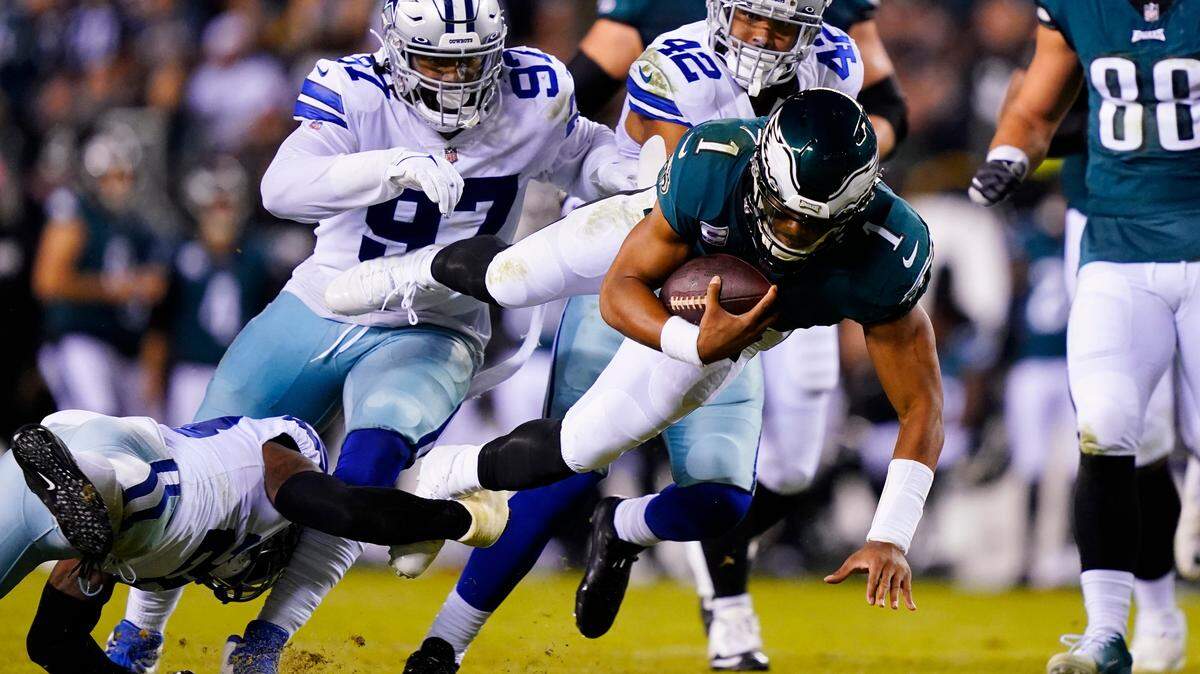 Philadelphia Eagles’ Jalen Hurts is brought down by Dallas Cowboys’ Malik Hooker, bottom, during their game in October. Hurts may not play on Saturday because of a shoulder injury.