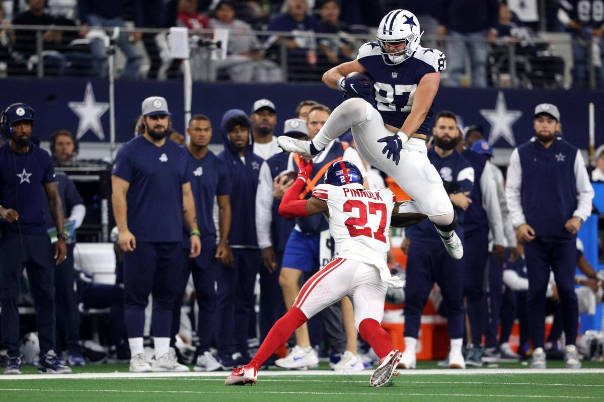 Dallas Cowboys tight end Jake Ferguson leaps over Giants free safety Jason Pinnock while driving the ball down the field during their game against the Giants at the AT&T Stadium in Arlington on Thursday, Nov. 24, 2022.