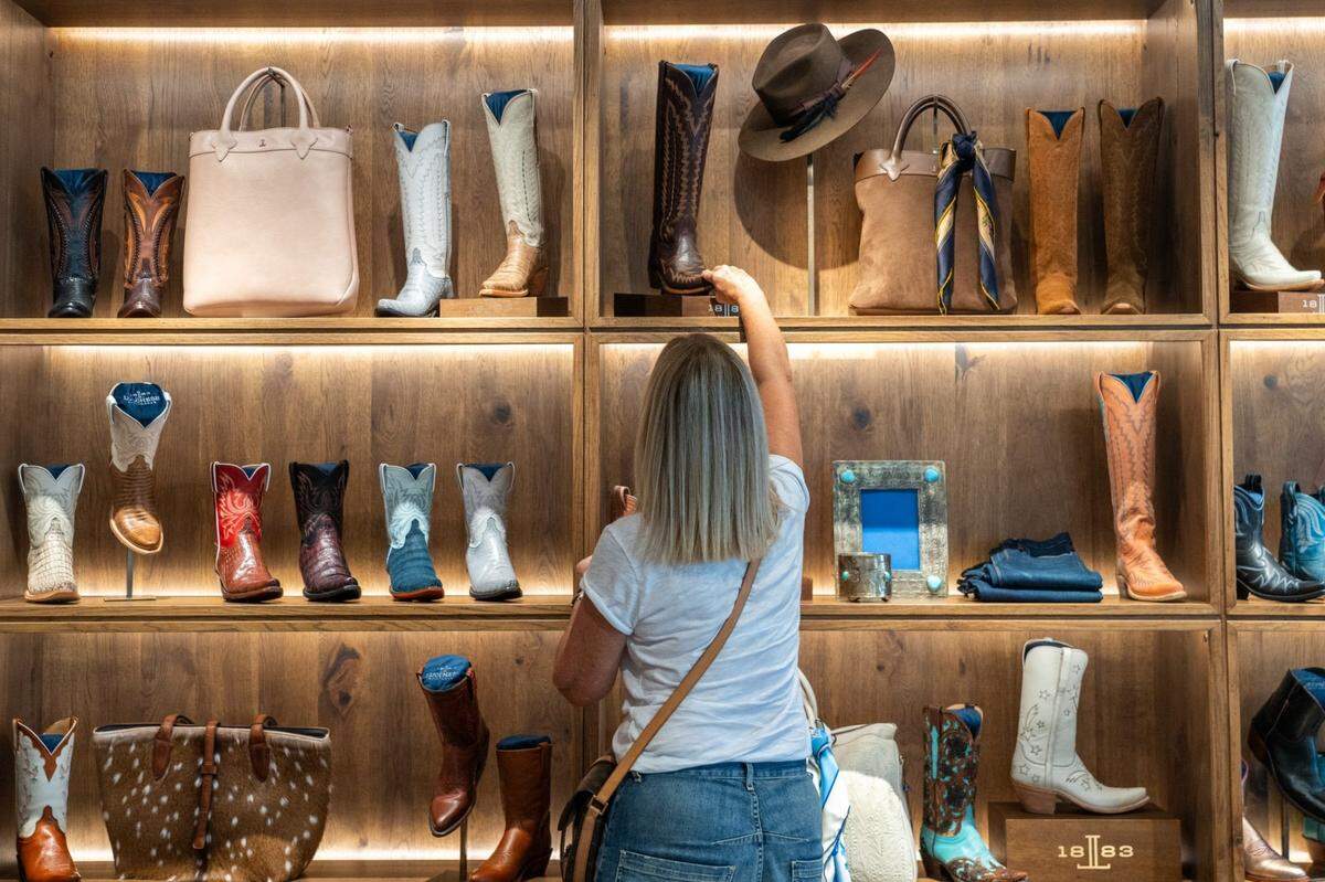 Cindi Carper reaches to examine a boot at Lucchese Bootmaker at the Domain Thursday, Aug. 22, 2024.