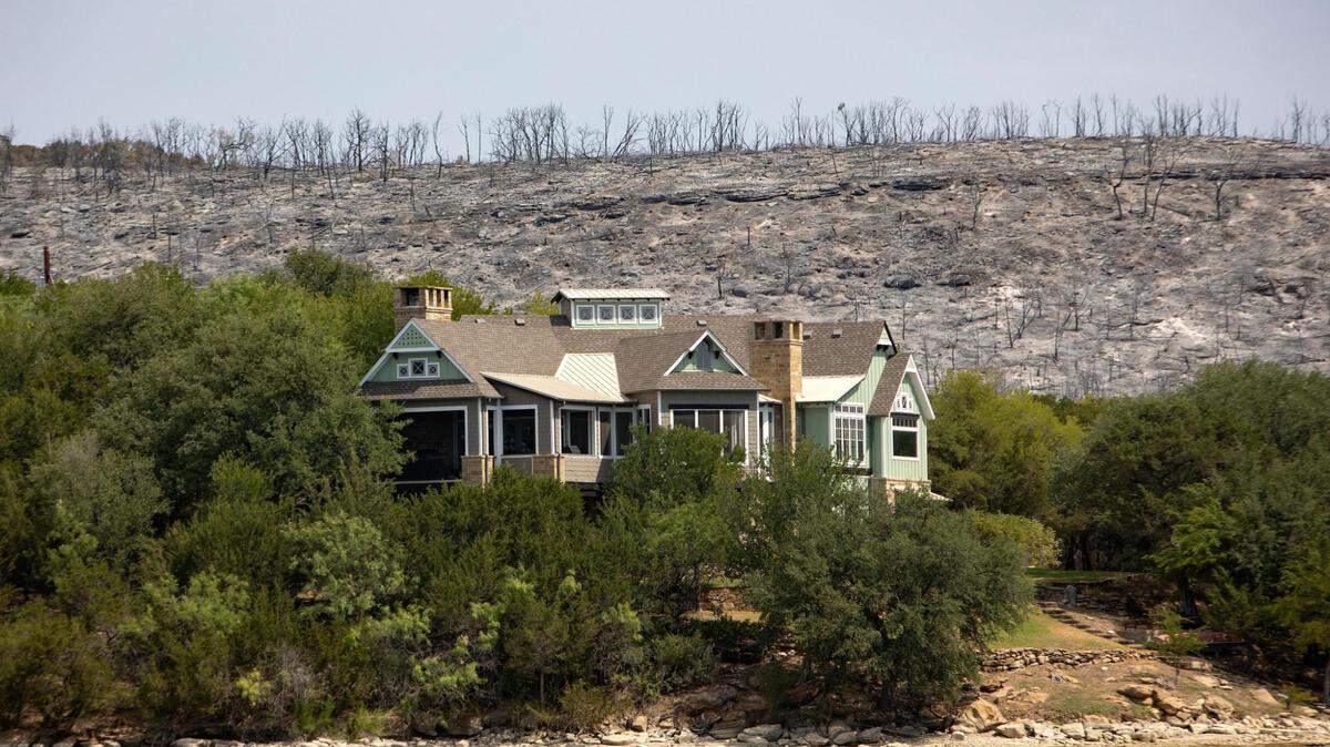A house remains unaffected after a wildfire on the coast of Possum Kingdom Lake in Graford, Texas, on Wednesday, July 20, 2022. The state’s dry conditions contributed to wildfires in 2022.