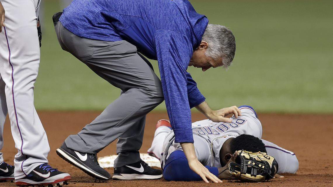 Head athletic trainer Kevin Harmon tends to Jurickson Profar on Monday after the shortstop landed on his head following a second-inning tumble near second base.