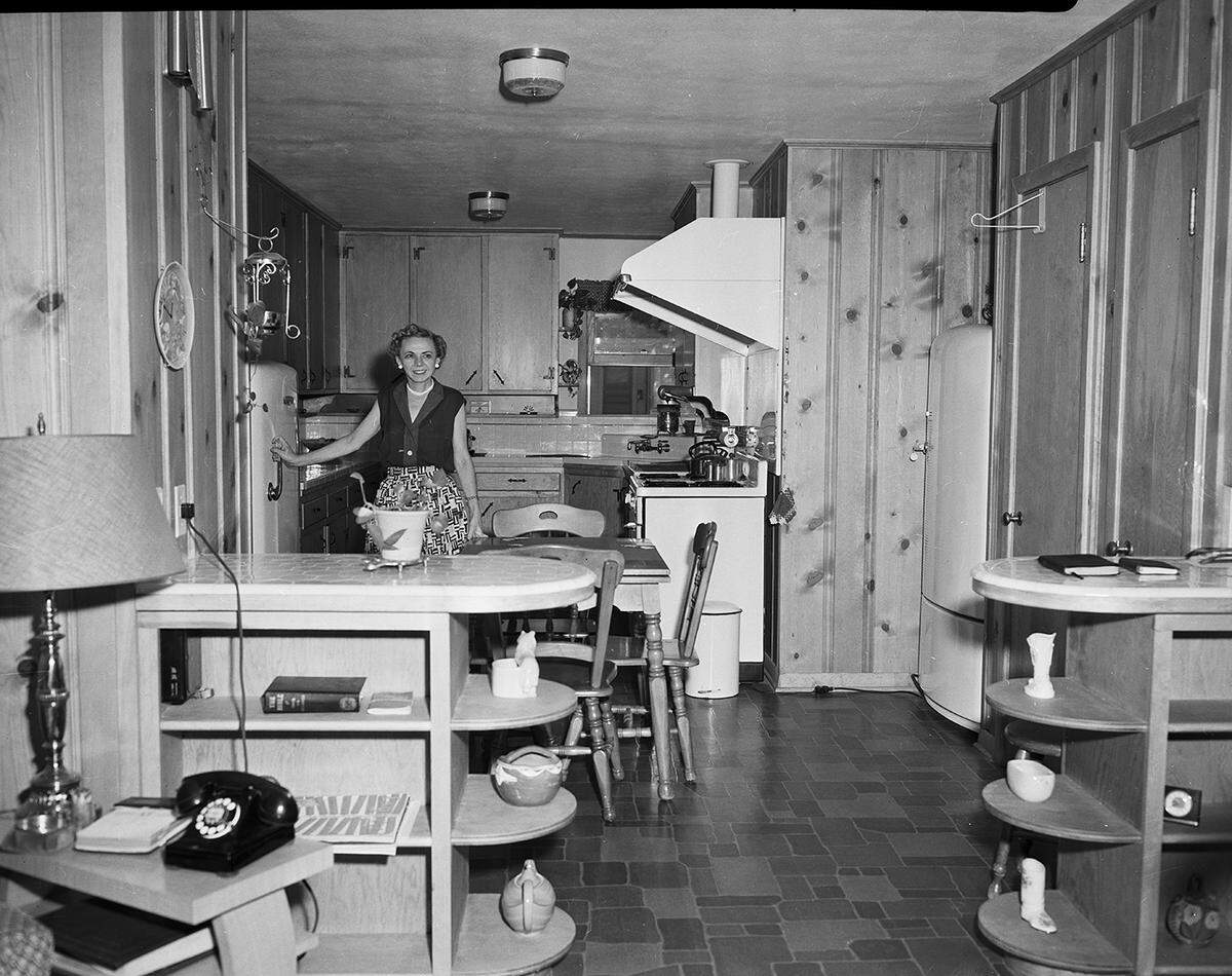 Sept. 3, 1952: A view of the wood-paneled kitchen in the new home of Miss Hudgins, as seen from the dining area. Tiled service bars flank the passage between the two rooms.