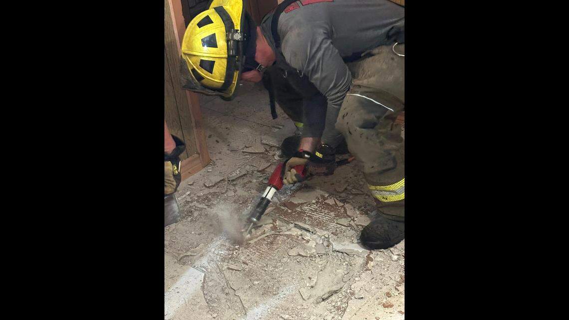 A firefighter drills into flooring. A firefighter drills into flooring.