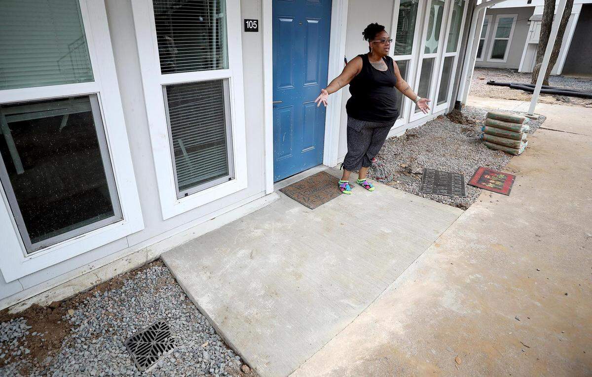 In this August 2021 photo, Rhonda Wallace shows where water used to gather and flood through her apartment door when it rained at Paddock on Park Row Apartments in Arlington. The complex cleared gutters outside her door, and installed new drains and concrete leading up to her doorstep. Starting in the new year, Texas landlords will have to disclose to potential renters if a property is in a floodplain or if it has been damaged by flooding in the past.