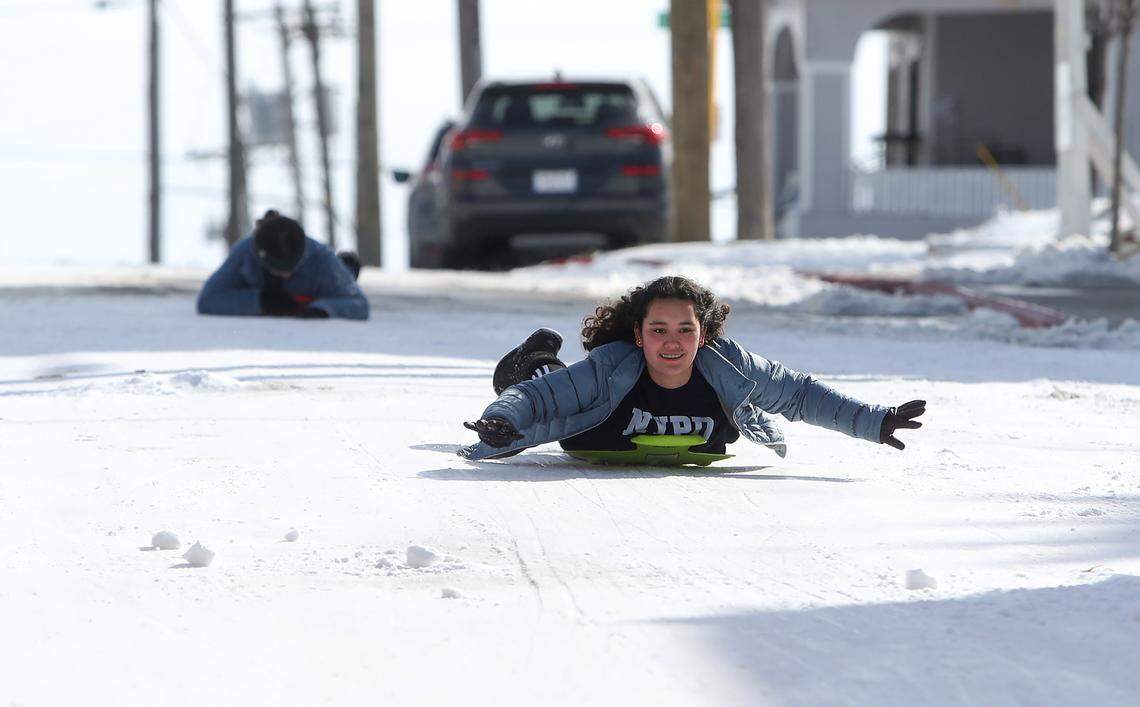 Maddy Howard, 15, right, and her sister Jane, 10, sled down a hill on Bryan Avenue in the Near Southside neighborhood of Fort Worth on Feb. 18, 2021.