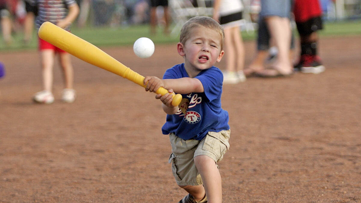 In this July 3, 2014, file photo, 3-year-old Logan McEwan gets in some batting practice with his dad at Roanoke’s Independence Day Celebration at Roanoke Community Park. Dad said that his baseball playing has progressed to the point Logan only wants to go to a park and play. He runs all of the bases after he gets a hit.