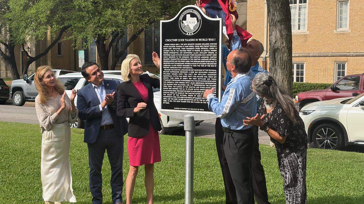 The unveiling of a Texas Historical Marker at Fort Worth’s Veterans Memorial Park to honor the first Native American code talkers to serve in the U.S. military, on Wednesday, April 1, 2026. From left, Catherine McKnight, secretary of the Texas Historical Commission; Fort Worth City Council members Carlos Flores and Macy Hill; John Austin, assistant chief of the Choctaw Nation of Oklahoma (behind the sign); Gary Batton, chief of the Choctaw Nation of Oklahoma; and Nuchi Nashoba, president of the Choctaw Code Talkers Association.