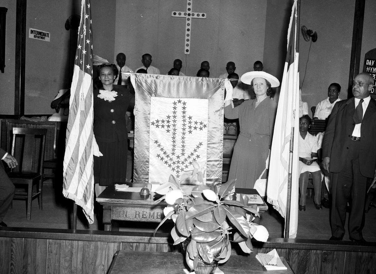 May 17, 1943: A service flag honoring 80 African-American men and one woman in the armed forces was dedicated at Saint Andrew’s Methodist Church in Fort Worth. Mable Motte Barnwell is standing and holding the flag at the left and Eula Mae Brooks is holding the right side.