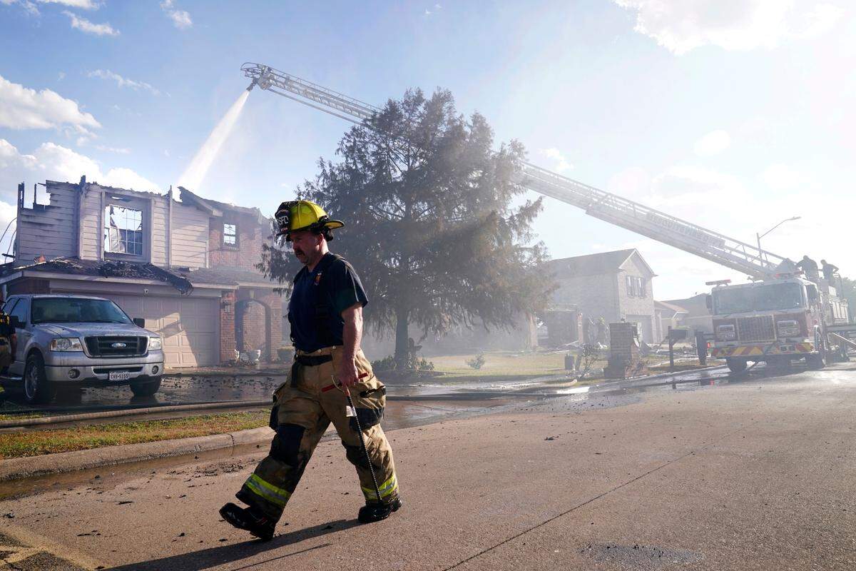 Firefighters from multiple departments work on putting out hot spots when a nearby grass fire damaged at least 26 homes Monday in Balch Springs.