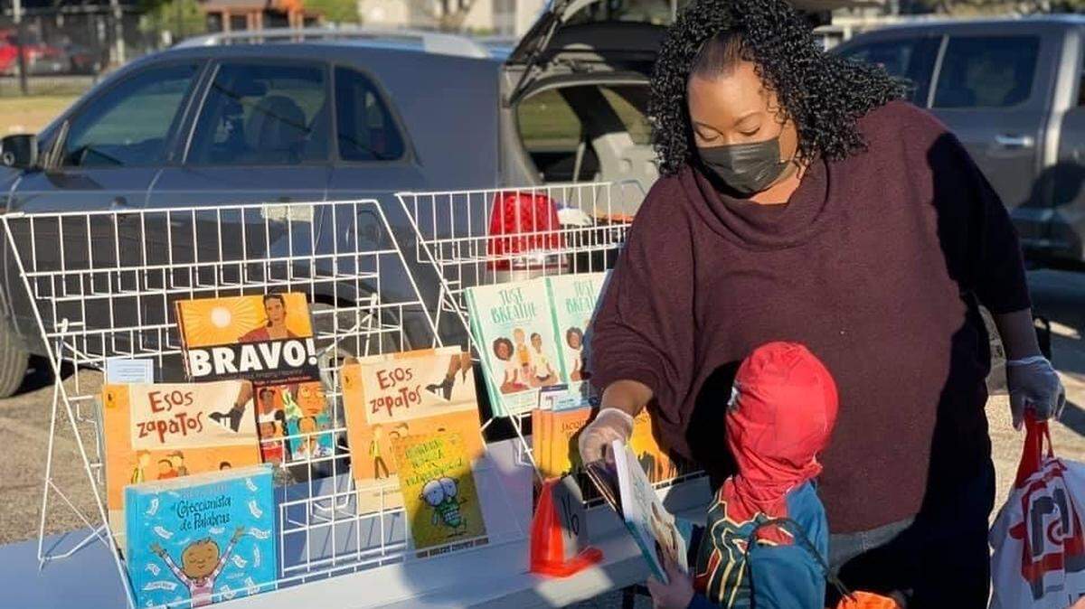 A youngster at the LVTRise Community Center receives a book from Rise Branch Library Assistant Tracy Lane during a neighborhood event. The Rise Branch Library is a Fort Worth Public Library onsite within the center that numerous children and families utilize throughout the year.