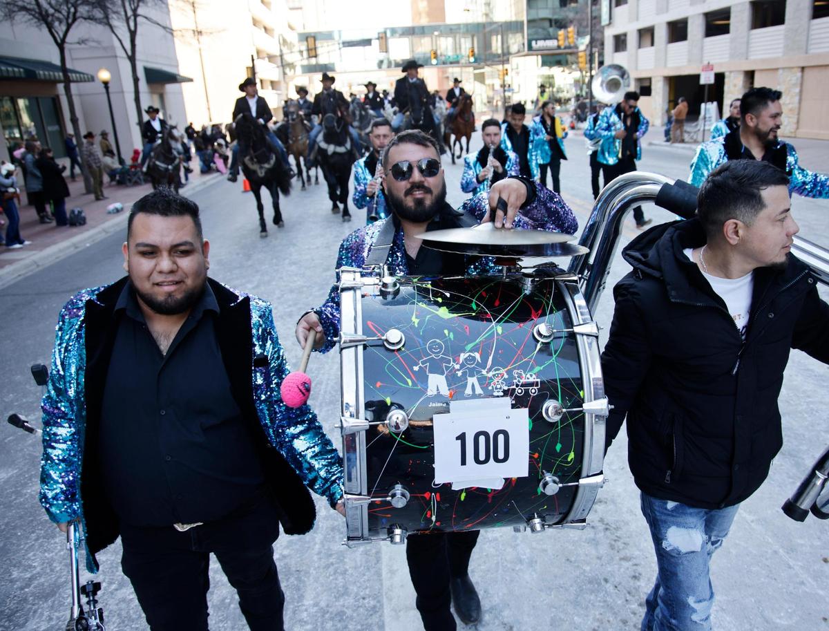 A band member gets help carrying his drum.