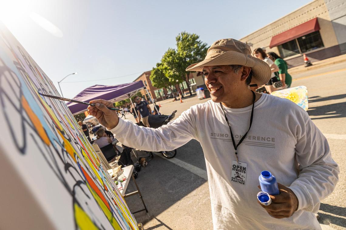 An Artist paints an art piece at Open Streets on Magnolia Avenue in Fort Worth on Saturday, April 13, 2024. Open Streets is a national movement encouraging innovative ways to achieve environmental, social, economic, and public health goals by temporarily closing streets to automobile traffic, so that people may use them for walking, bicycling, dancing, playing, and socializing.