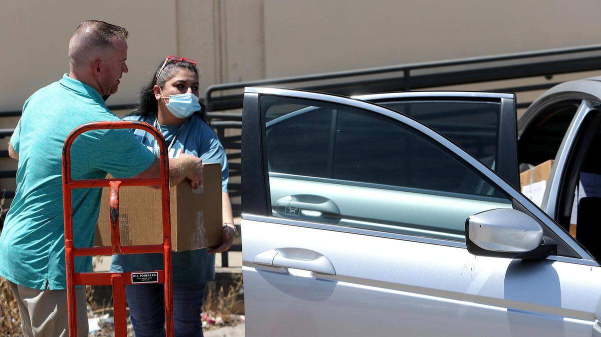 Nathan Wright and Yolanda Veloz load Chromebooks and Wi-Fi hotspots into a Fort Worth ISD campus representative’s car on Aug. 12. Fort Worth district officials plan to offer broadband service in four neighborhoods after summer break.