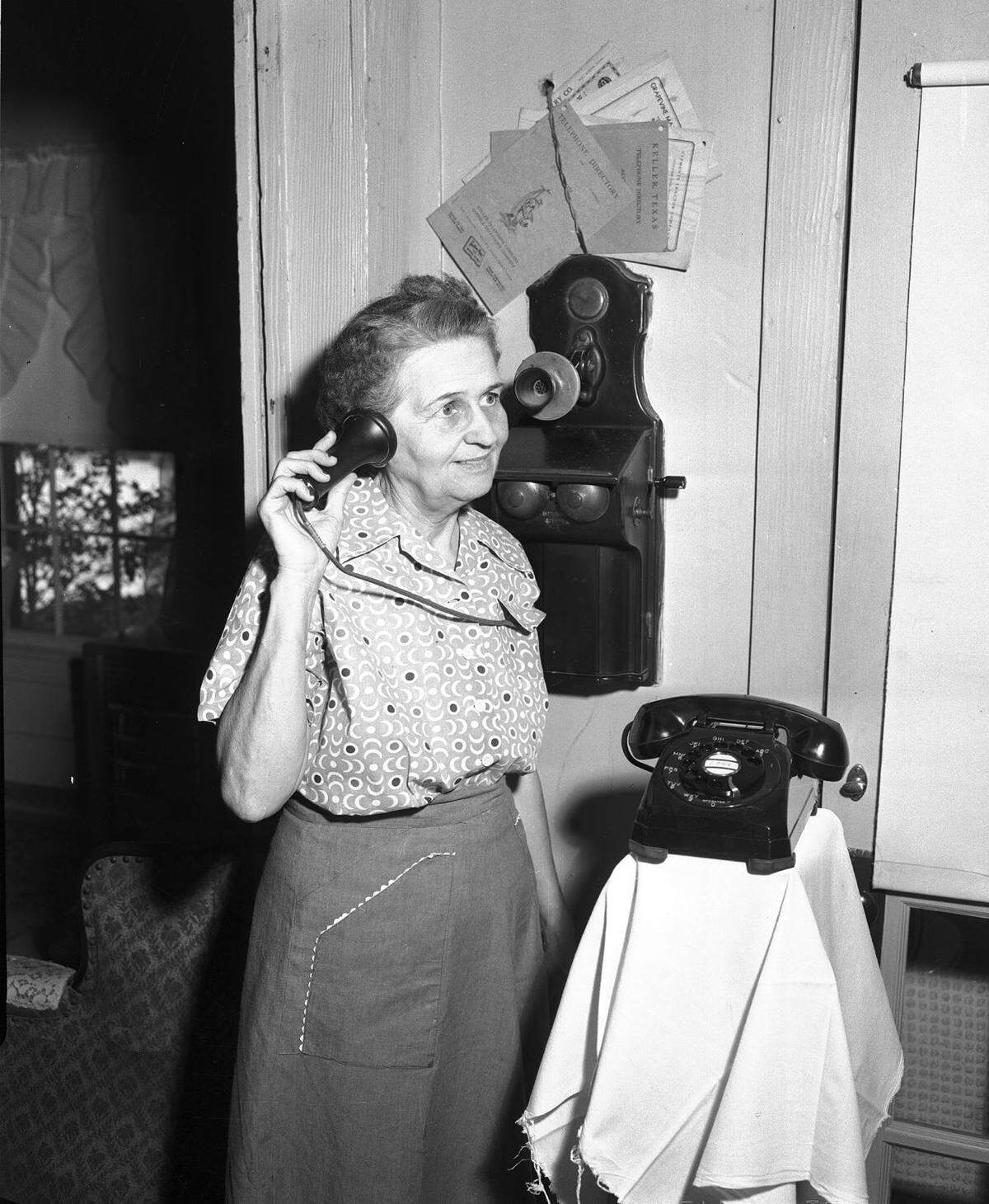 Aug. 5, 1954: Mrs. Mabel Scott of Keller makes a call on old-time magneto wall telephone.