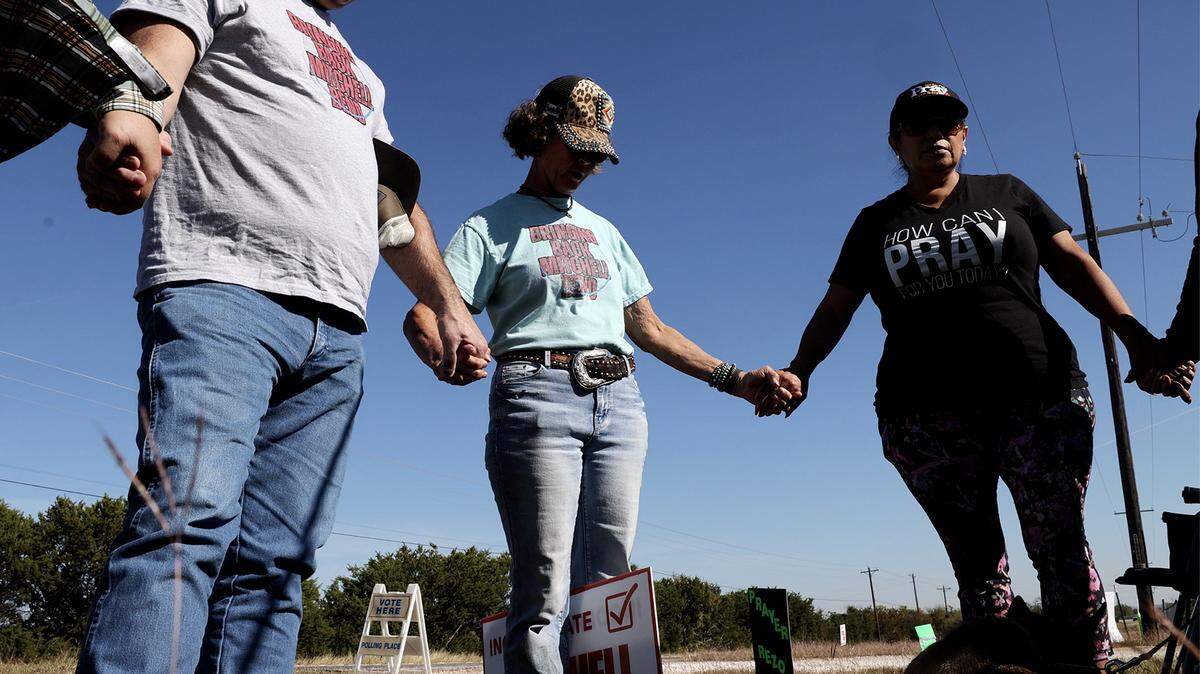 Danny Lakey, left, and Cheryl Shadden, center, pray with fellow community members outside of Brazos River Baptist Church on Tuesday, Nov. 4, 2025. Voters will decide whether area around Mitchell Bend Highway will incorporate as a city during the election.