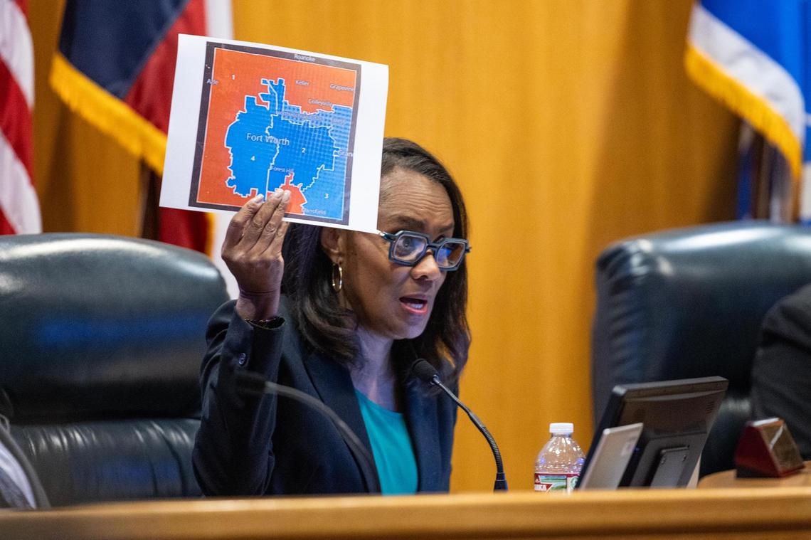 Alisa Simmons, Tarrant County commissioner for Precinct 2, holds up a map reflecting blue precincts in the county during a Tarrant County Commissioners Court meeting at the Tarrant County Administration Building in Fort Worth on June 3, 2025.