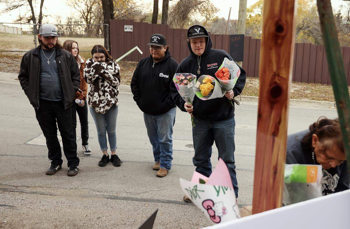 Jordan Clair, right, and friends place flowers at a memorial for his brother Blake Bullock on Tuesday, Dec. 16, 2025. Bullock’s body was lying on Northwest 20th Street on the night of Dec. 15, 2025, and was subsequently struck by a police vehicle responding to a report of gunfire.