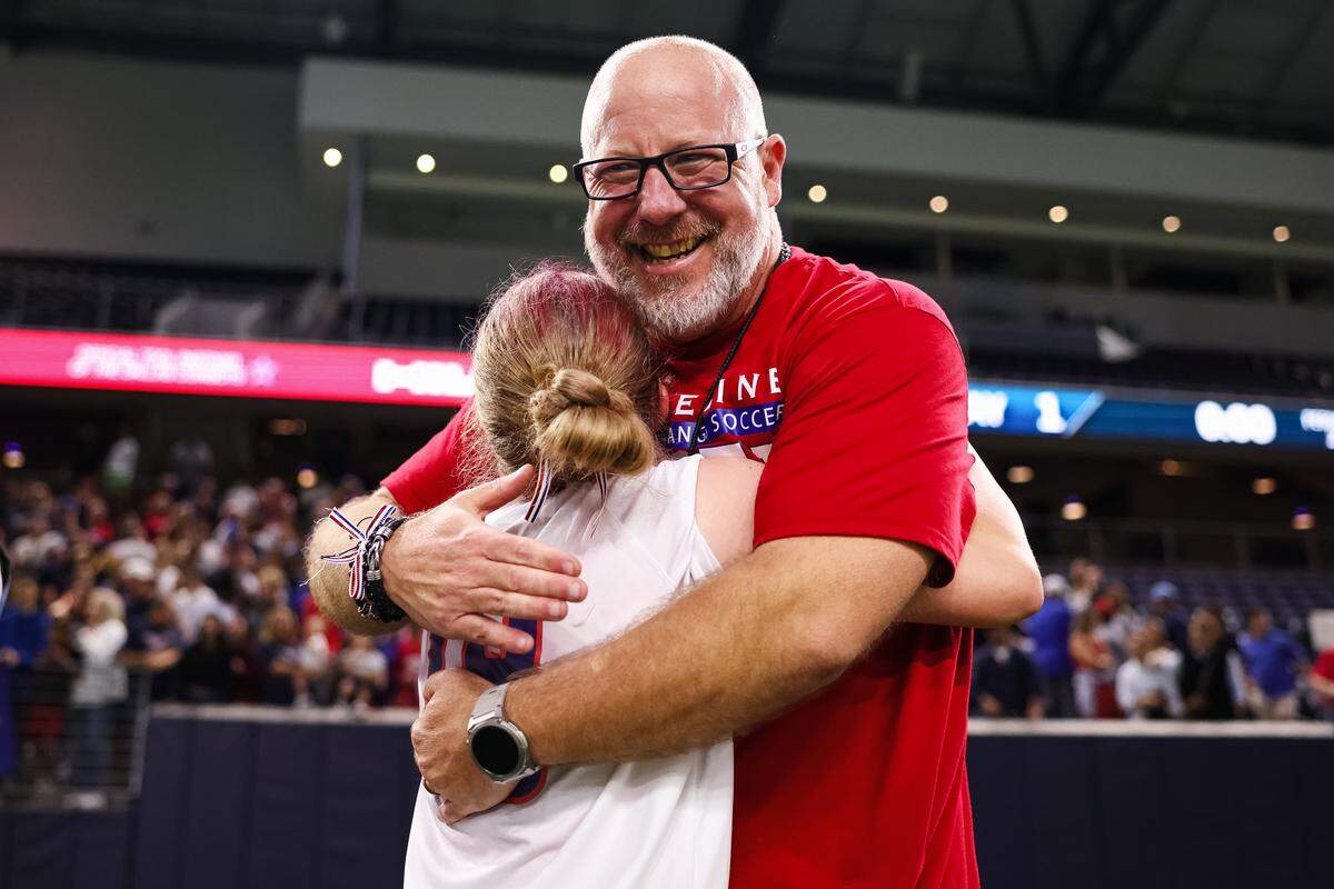 Grapevine head coach Steve McBride hugs one of his players in celebration after defeating Frisco Wakeland in a Class 5A Division  II UIL girls soccer state semifinal at the Ford Center on April 3, 2026 in Frisco, Texas.