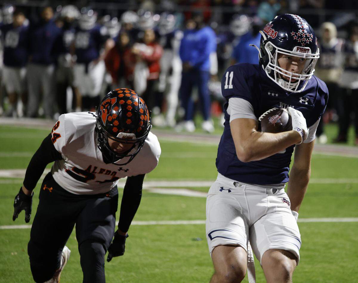 Denton Ryan wide receiver Connelly Cunningham (11) scores ahead of Aledo corner back Blaine Fisher (24) during the second half of a UIL Class 5A Division I Quarterfinal on Friday Dec. 05, 2025 at Northwest ISD Stadium in Fort Worth, Texas.