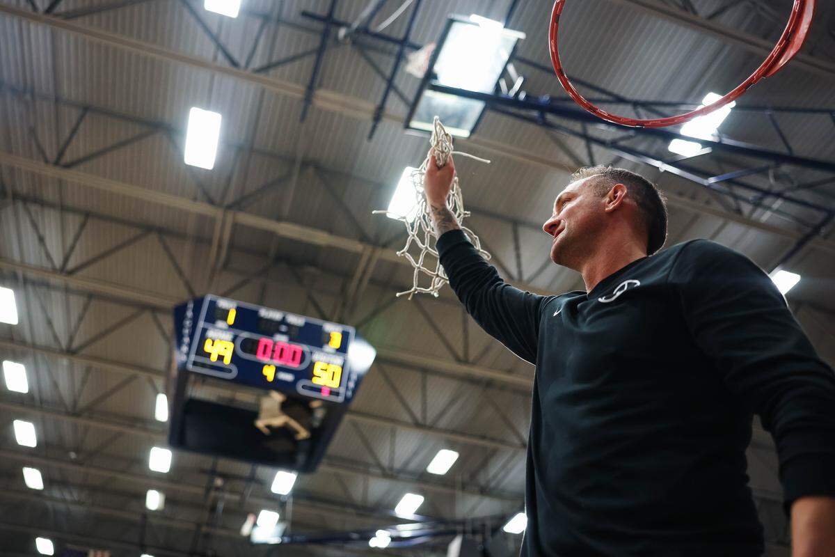 Birdville head coach Anthony Holman holds up the fully cut net toward the Birdville crowd after clinching a spot in the state semifinals after a 50-49 UIL Class 5A Division I regional final win against Denton at Flower Mound High School in Flower Mound, Texas, Friday, March 6, 2026.
