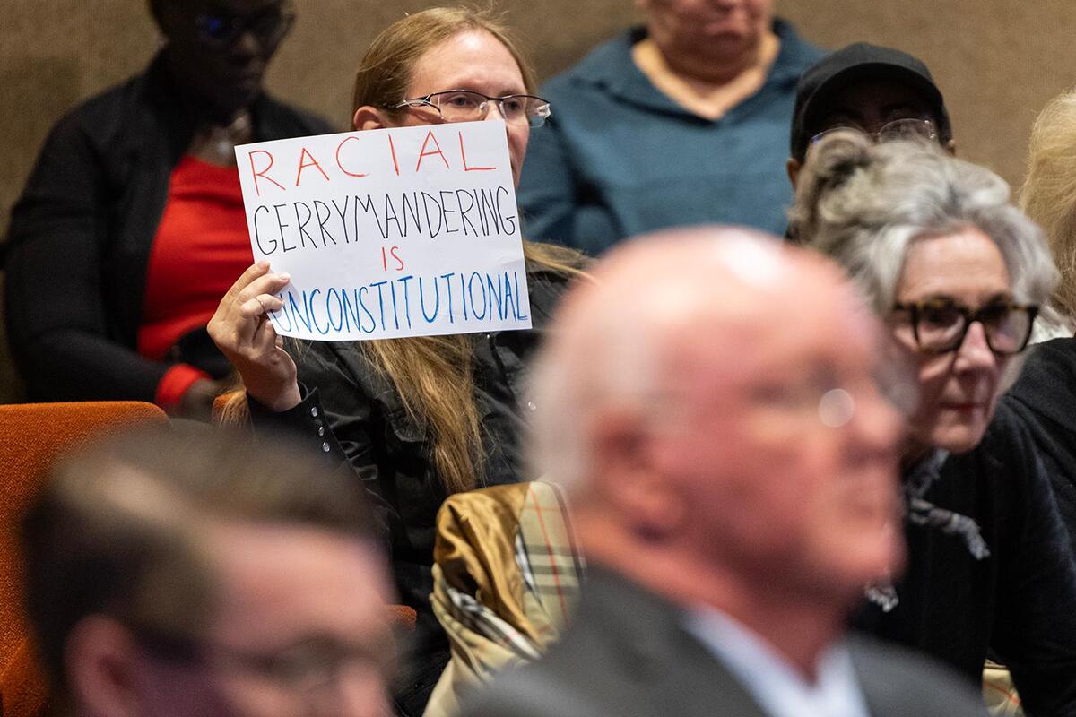Meeting attendee Crystal Betts holds up a sign protesting proposed redistricting during a Commissioners Court Meeting at the Tarrant County Administration Building in Fort Worth on May 6.