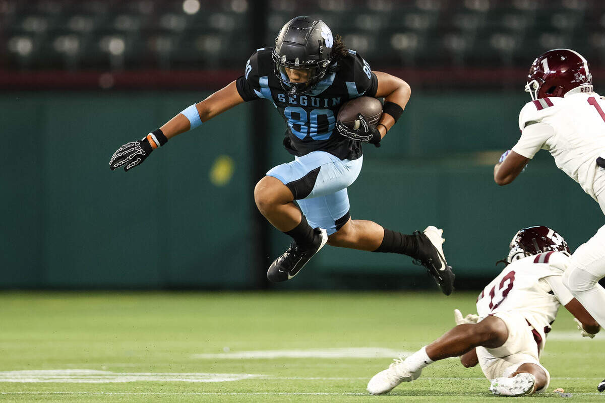 An Arlington Seguin receiver leaps in the air past a Red Oak defender in the second quarter of a non-district game between Red Oak and Arlington Seguin at Choctaw Stadium in Arlington, Texas on Sept. 4, 2025.