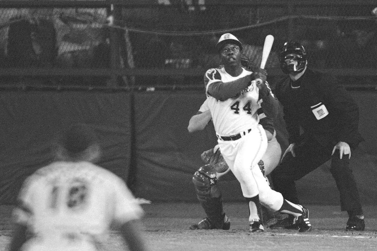 FILE - Atlanta Braves’ Hank Aaron eyes the flight of the ball after hitting his 715th career homer in a game against the Los Angeles Dodgers in Atlanta, Ga., in this April 8, 1974 file photo. Dodgers pitcher Al Downing, catcher Joe Ferguson and umpire David Davidson look on. Hank Aaron, who endured racist threats with stoic dignity during his pursuit of Babe Ruth but went on to break the career home run record in the pre-steroids era, died early Friday, Jan. 22, 2021. He was 86. The Atlanta Braves said Aaron died peacefully in his sleep. No cause of death was given. (AP Photo/Harry Harrris, FIle)