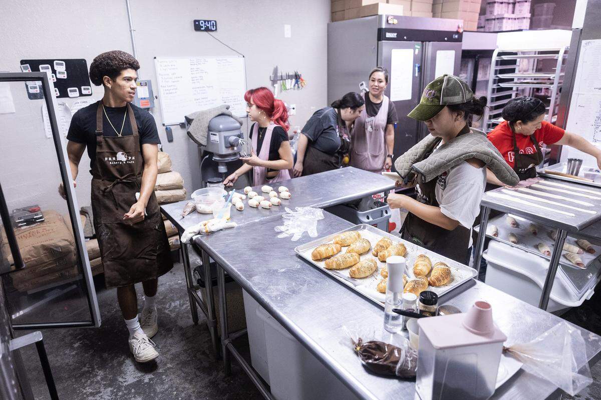 Bakery staff works together to make baked goods in the kitchen.