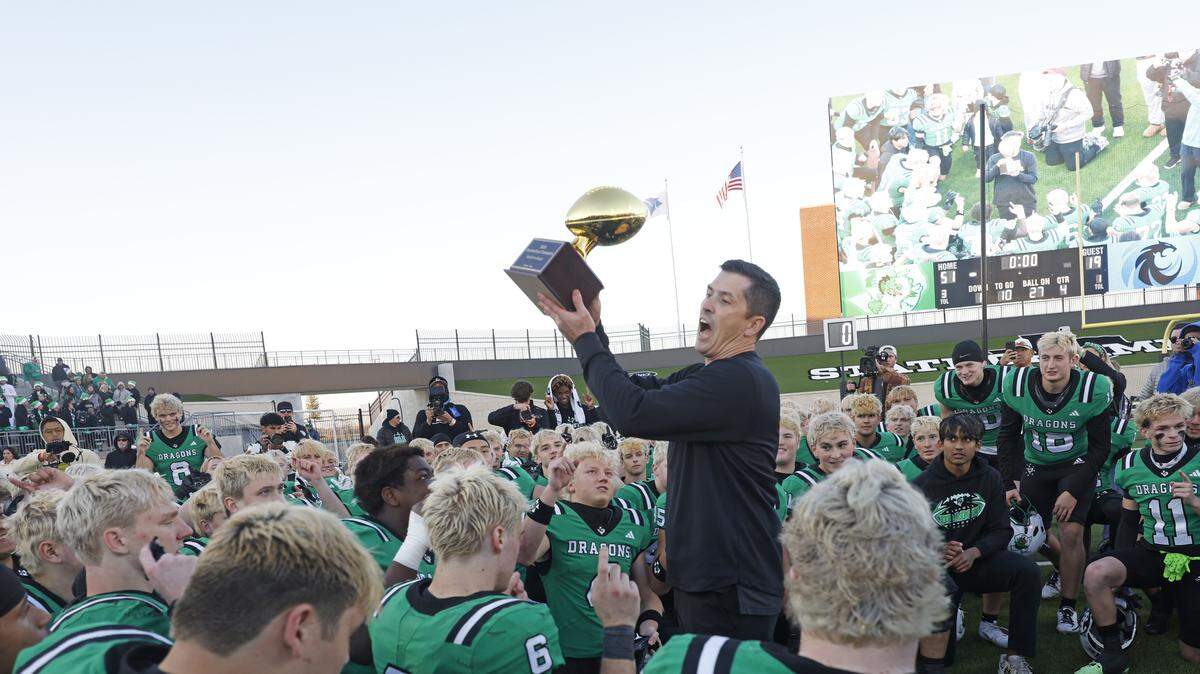 Southlake Carroll head coach Riley Dodge presents the trophy to the Dragons after defeating Denton Guyer in a Class 6A Division II state quarterfinal Dec. 6 at Crowley ISD Multi-Purpose Stadium.